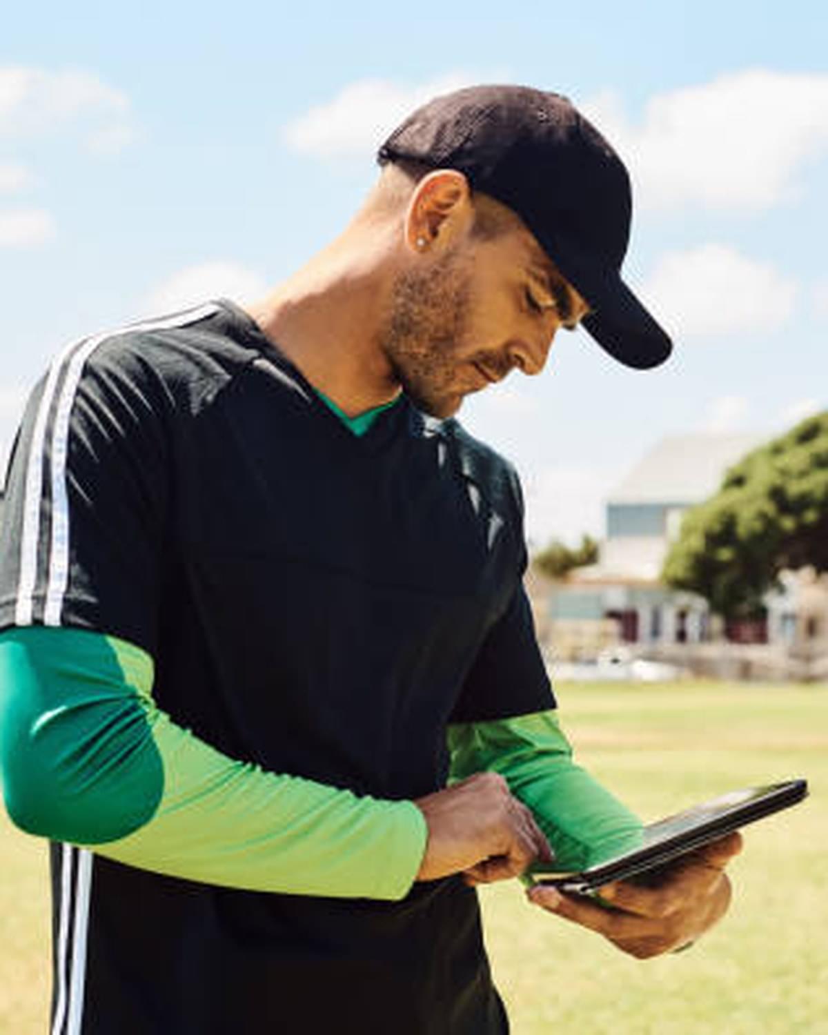 Coach with tablet, team around her in green bibs