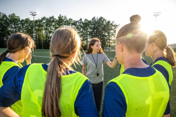 Coach leading a team huddle with young athletes